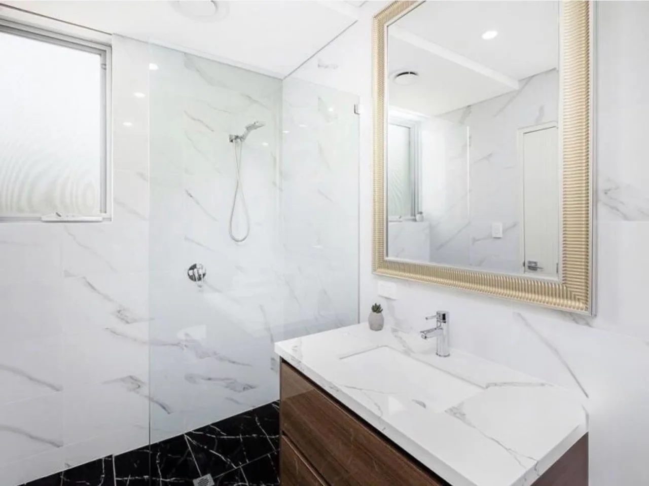 White bathroom with marble-patterned surfaces and a timber vanity