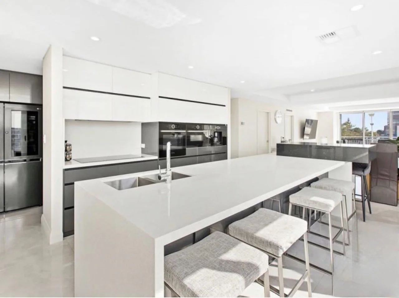 Bright kitchen with a white island, dark cabinetry and white ceiling