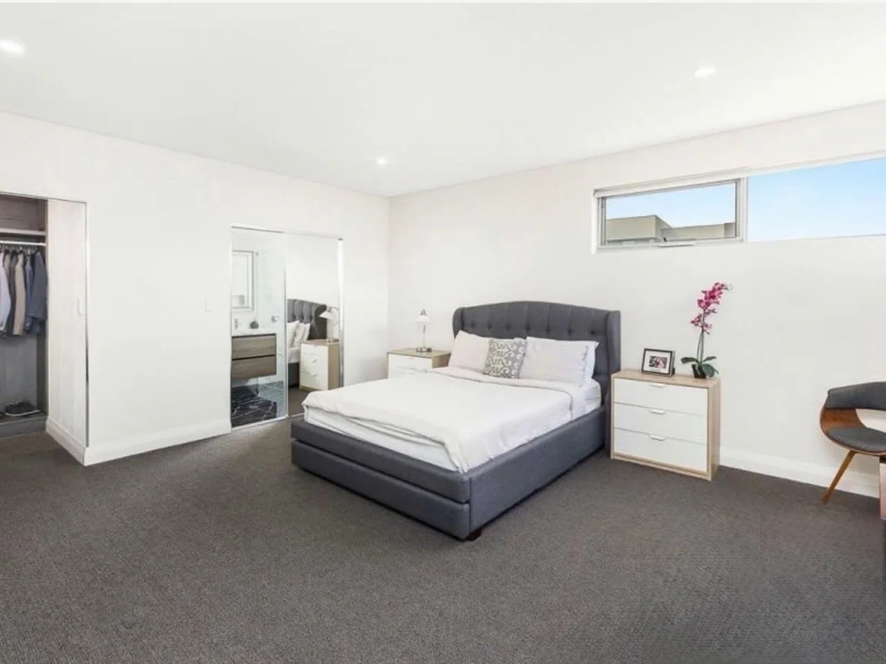 Spacious bedroom with clean white walls, ceiling and mirrored wardrobe